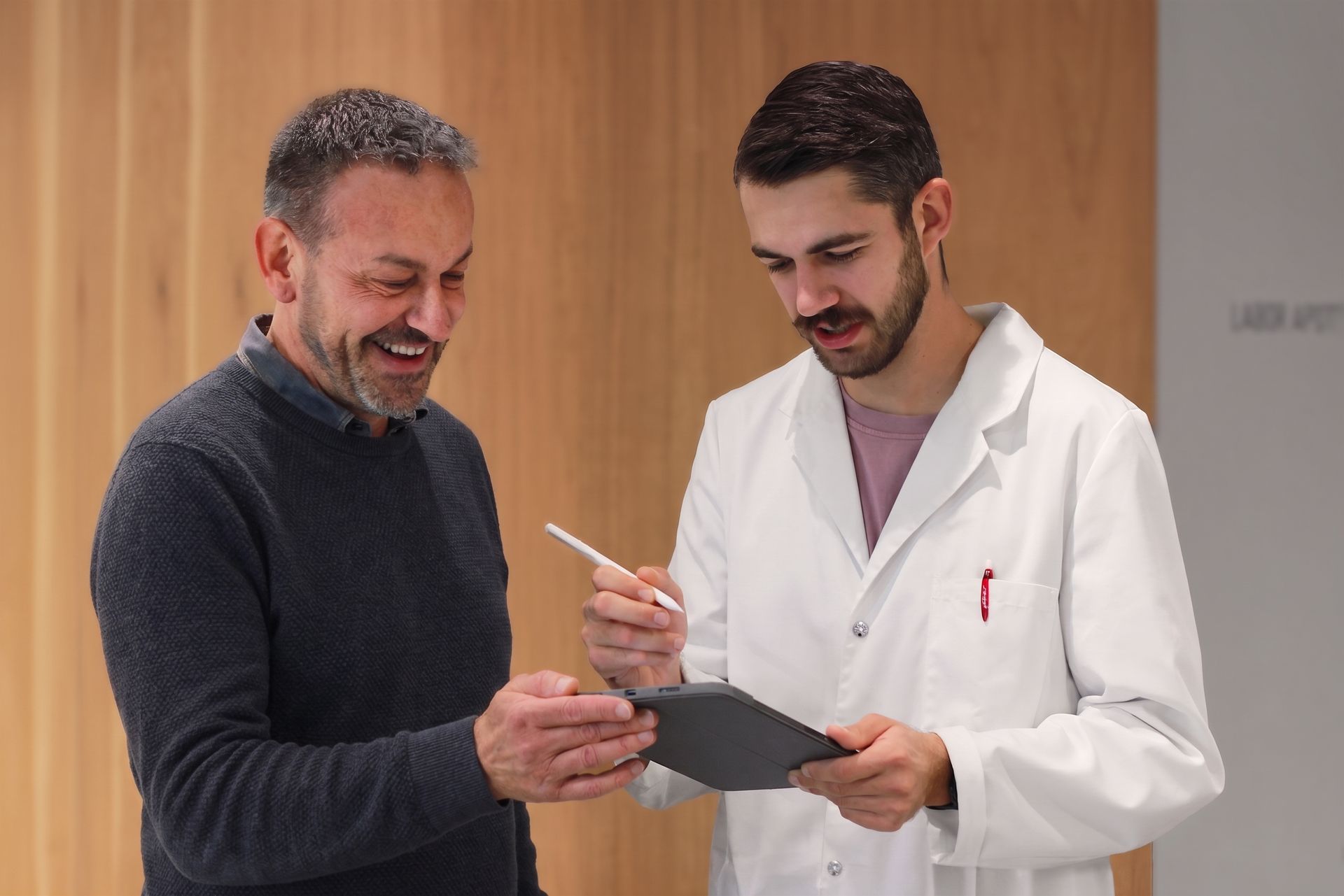 Apotheker bespricht mit einem Kunden Resultate auf einem Tablet